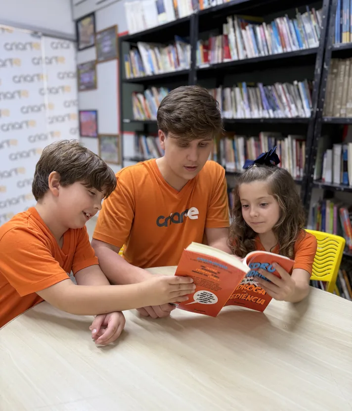 Alunos do Ensino Fundamental lendo juntos na biblioteca do Colégio Criarte